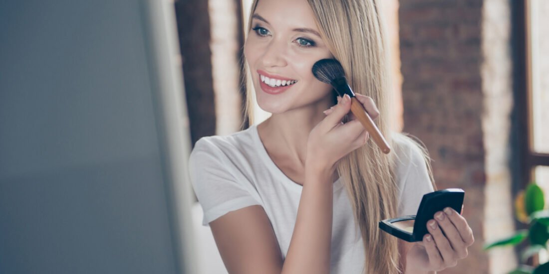 Young woman smiling and applying her daily makeup