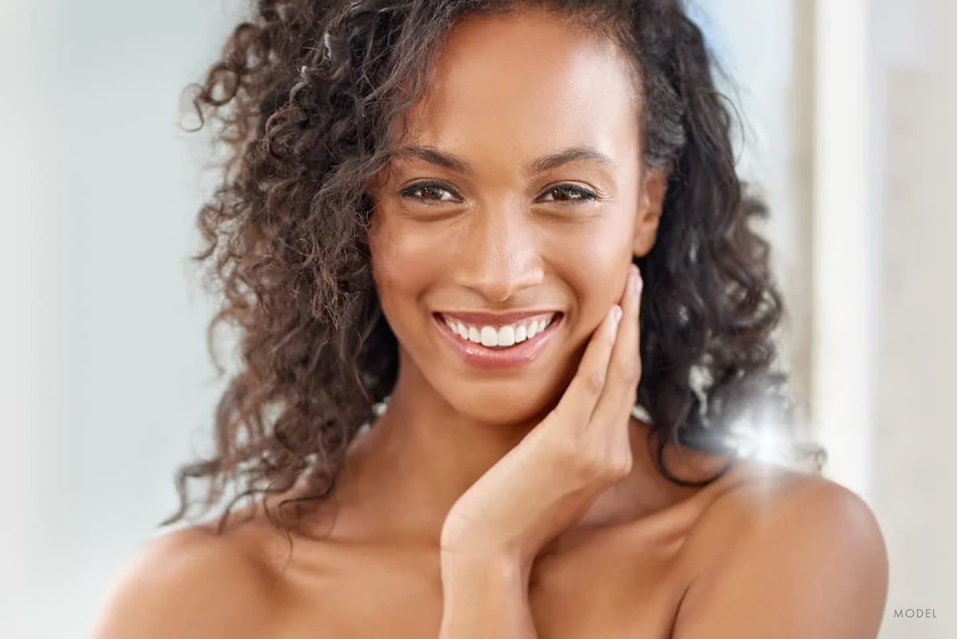 Woman smiling and looking in the mirror observing her healthy skin