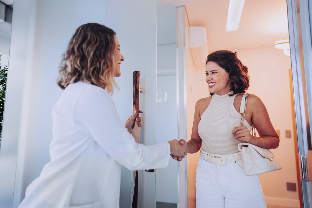 Woman smiling and shaking hands with a qualified provider at a safe, physician-owned medical spa