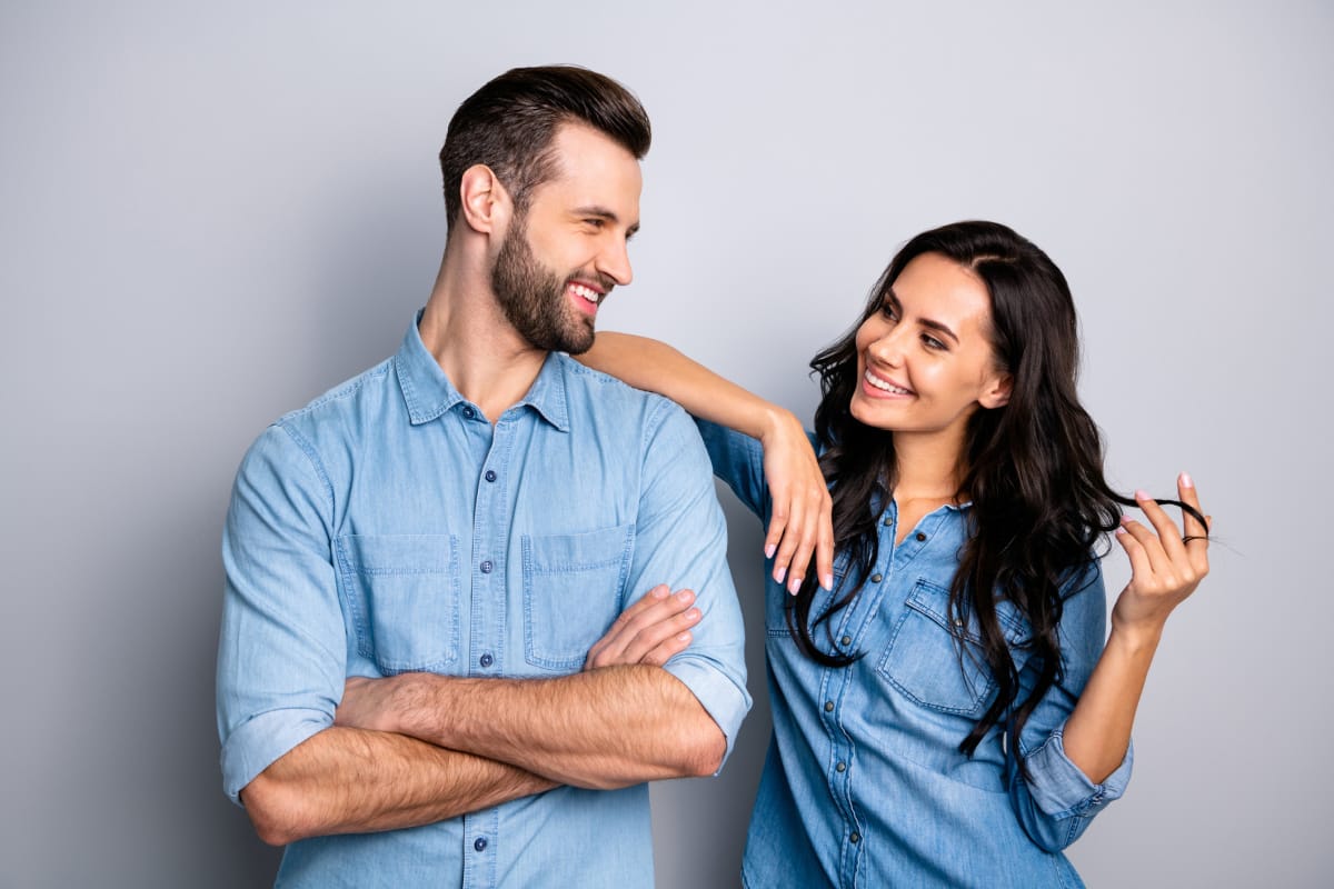 Man and woman with long, healthy hair smiling at each other